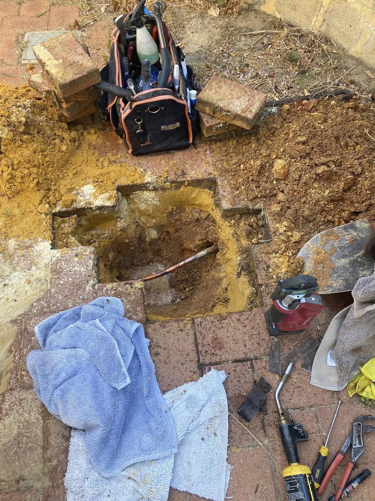 Repairing a leaking water pipe uncovered under paving
